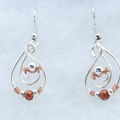 A pair of silver teardrop dangle earrings with copper wire swirls, small silver beads, and a round copper bead, displayed on a light gray textured background.