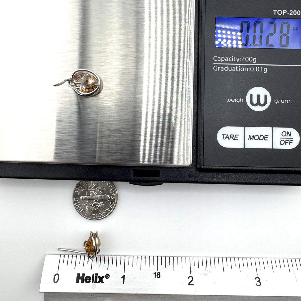 stud earrings are  shown on a digital scale with a coin and ruler below for scale, photographed on a white surface.
