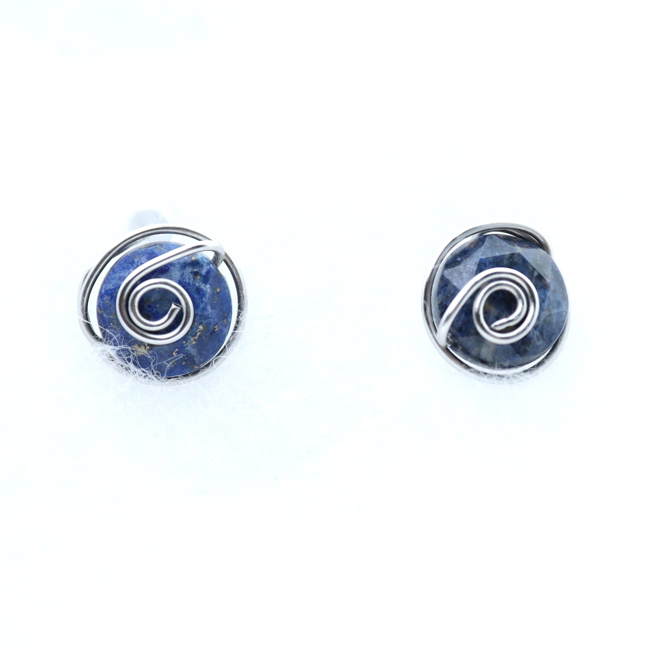A pair of handmade wire-wrapped earrings featuring dark blue aventurine 10mm faceted stones held in hand-shaped stainless steel spiral wire details, set against a plain white background.